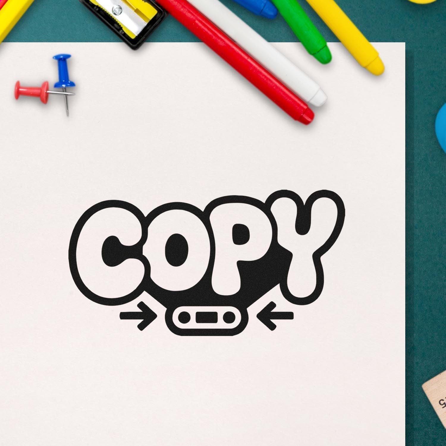 Bold COPY rubber stamp impression on paper, with colorful markers and pushpins framing the design.