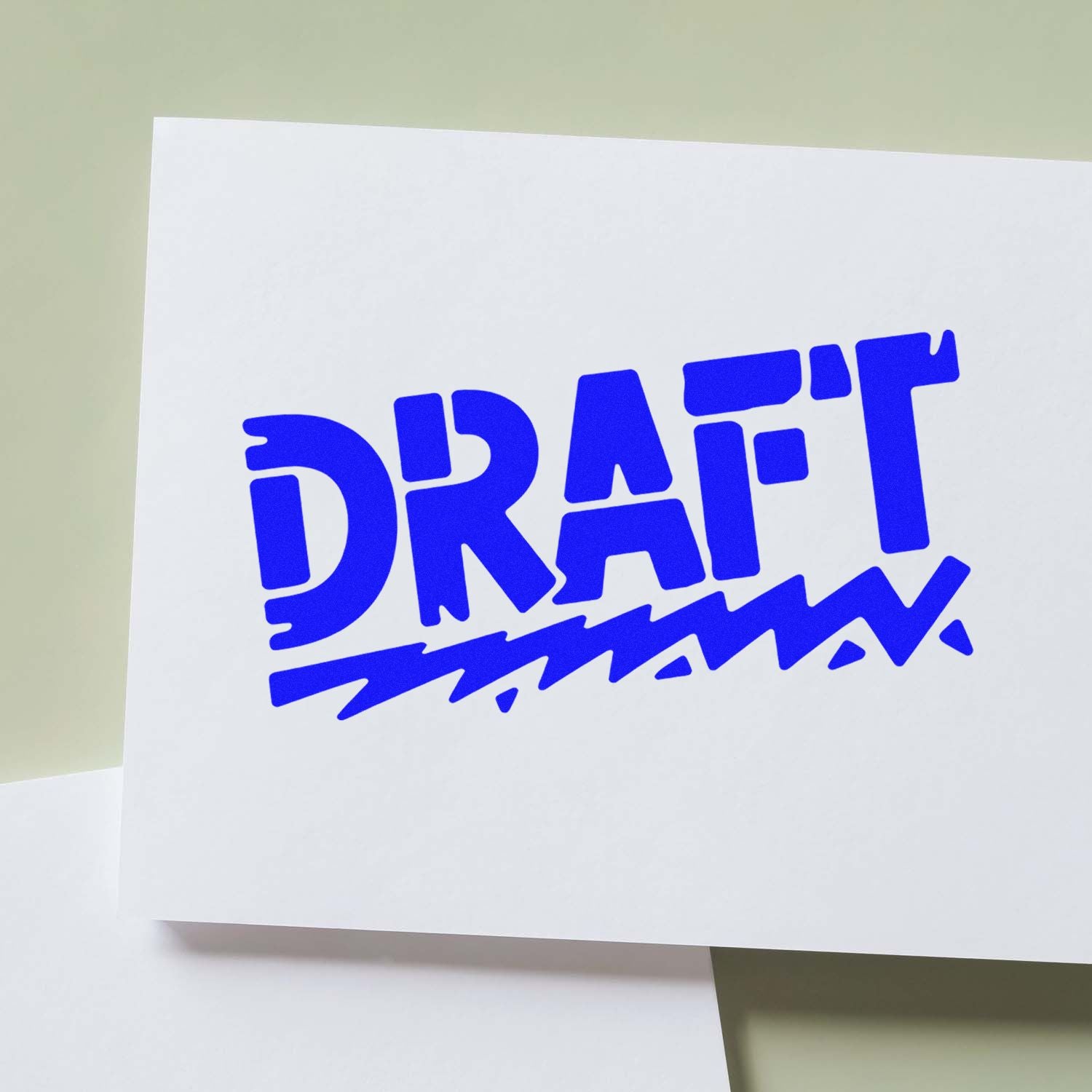 Blue DRAFT rubber stamp impression on white paper for document review and approval