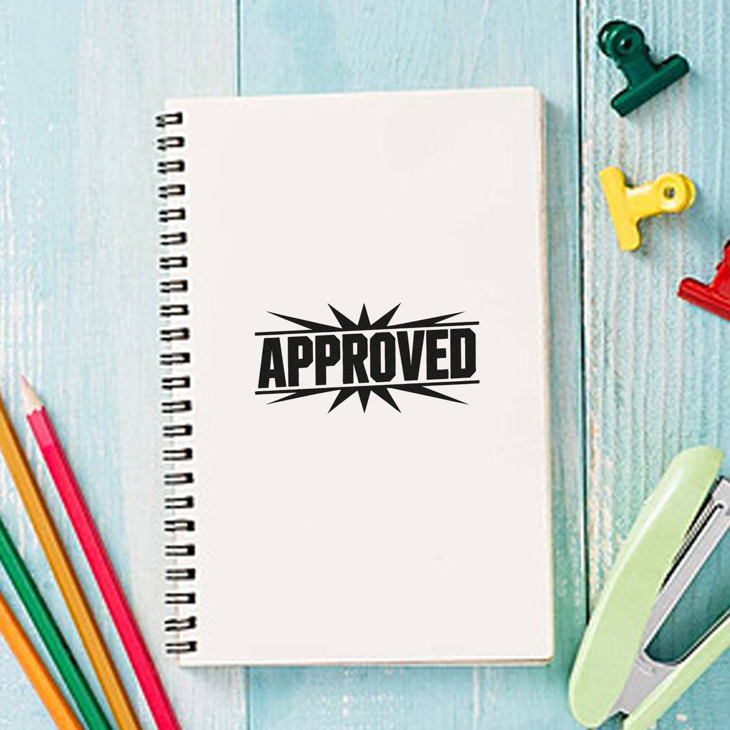 Approved rubber stamp on a notebook, with colorful stationery on a desk for office or school use.