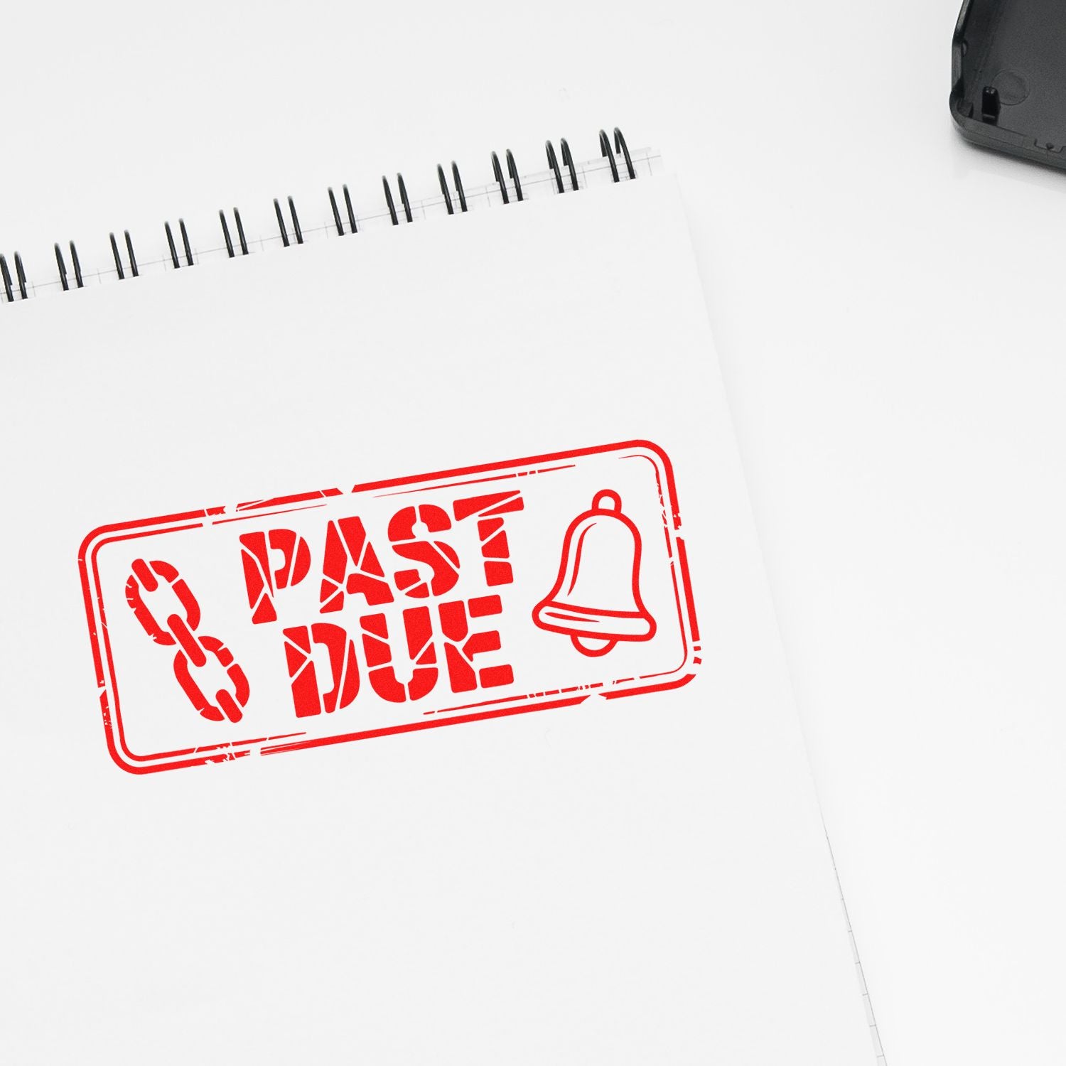 Red past due rubber stamp with chain and bell icon on notebook page, ideal for overdue payment reminders and billing notices.