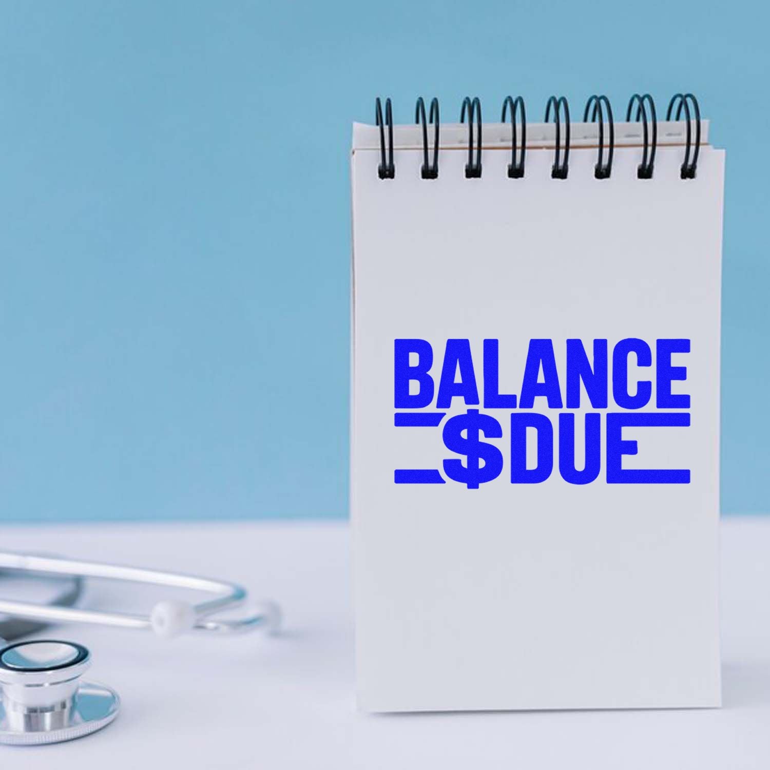 Blue BALANCE DUE rubber stamp on notepad, ideal for medical billing and accounts receivable reminders