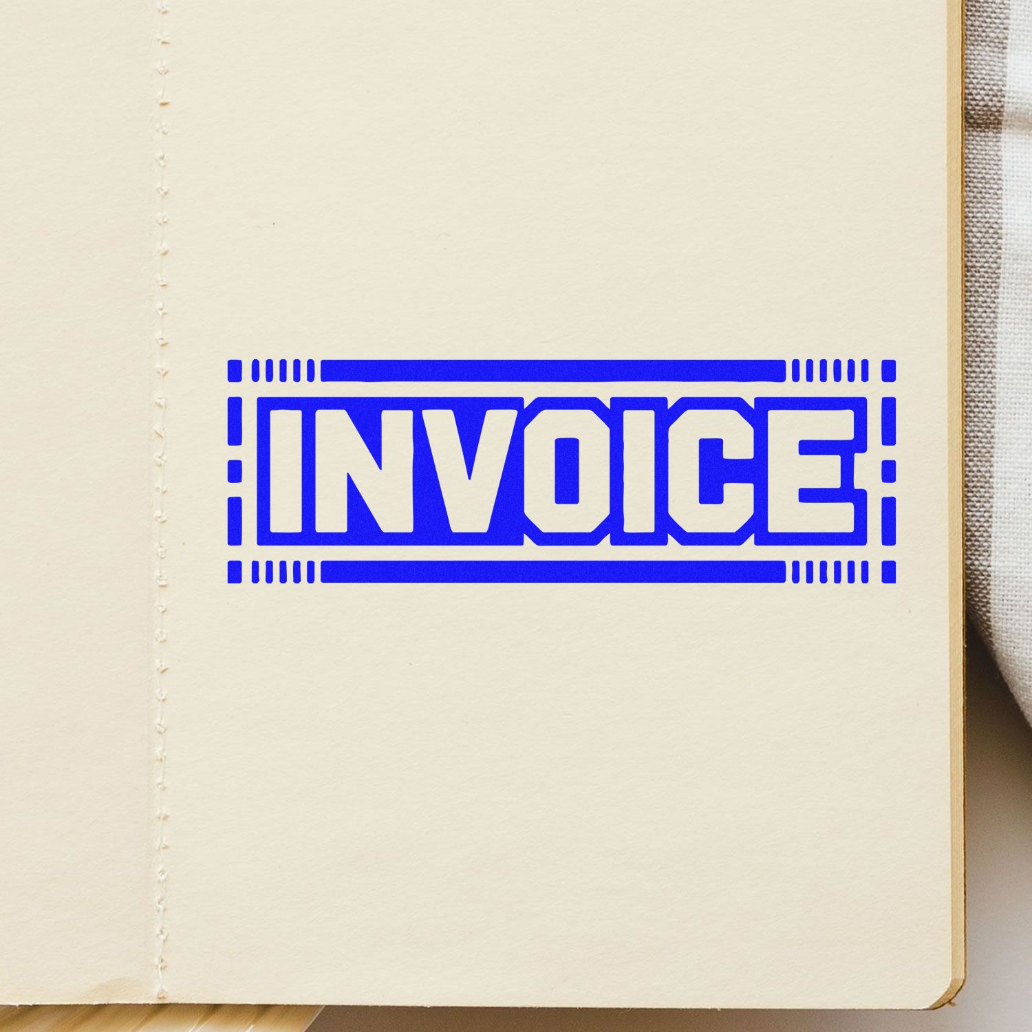 Blue invoice rubber stamp impression on notebook page for billing, accounting, and business records.