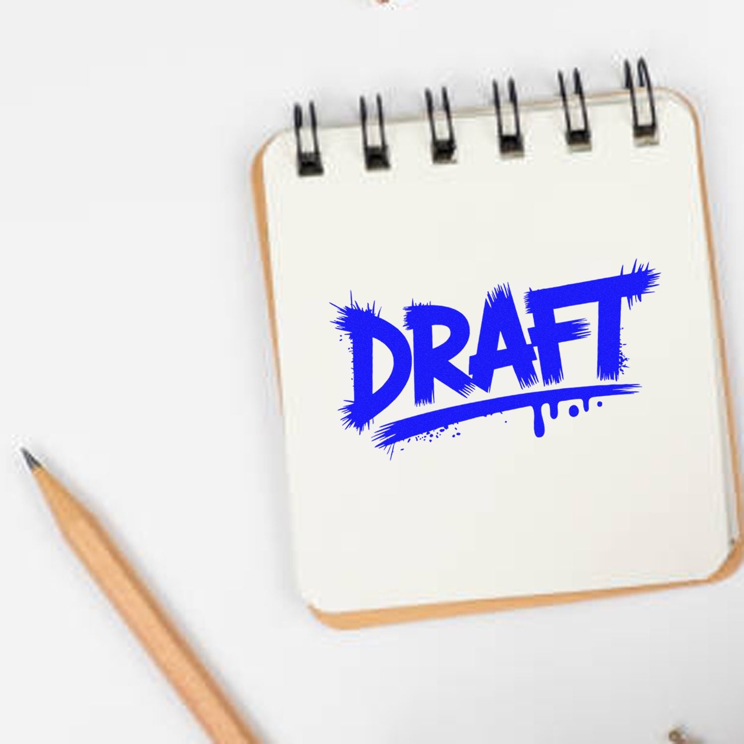 Blue DRAFT rubber stamp on notebook with pencil, for marking document drafts and office paperwork.