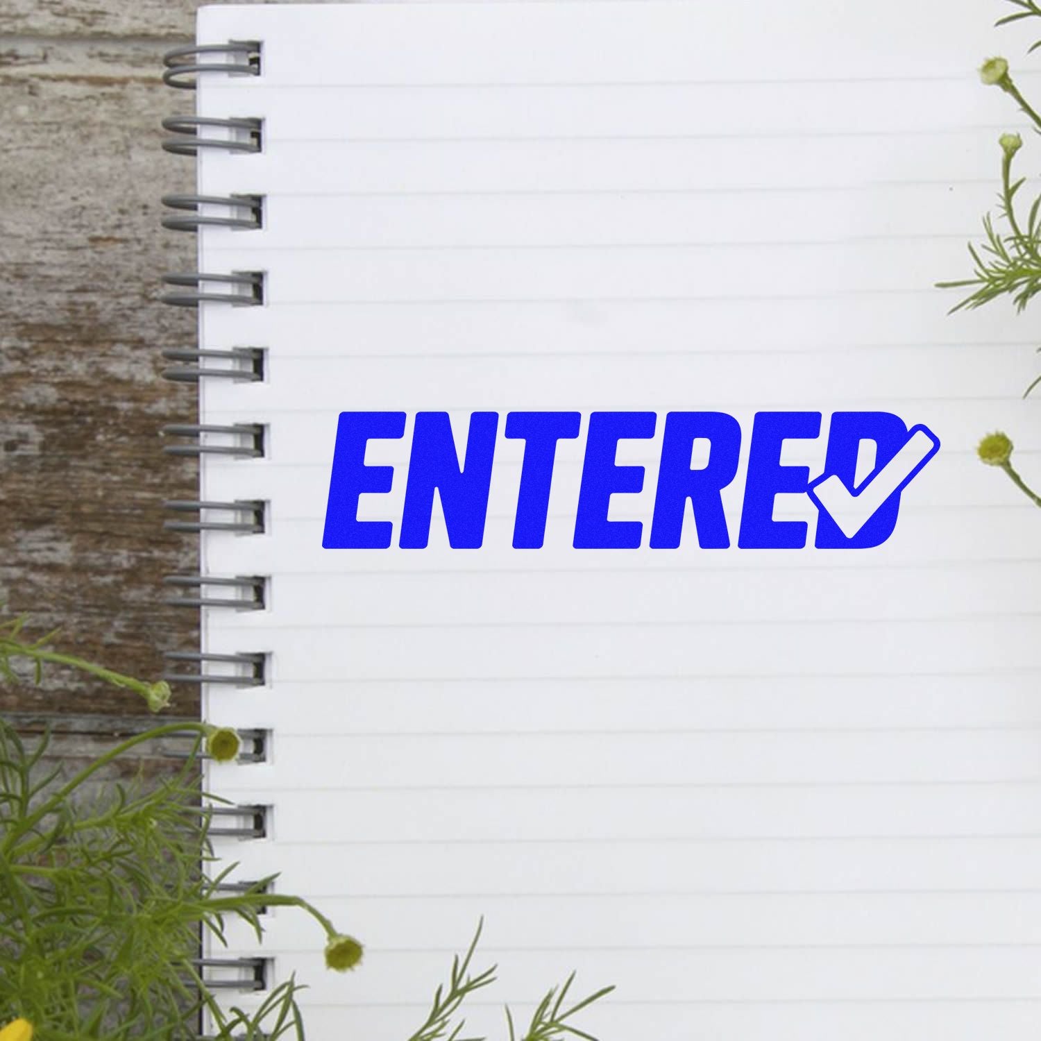 Blue ENTERED rubber stamp with check mark on notebook page, ideal for office document processing and approval tracking.