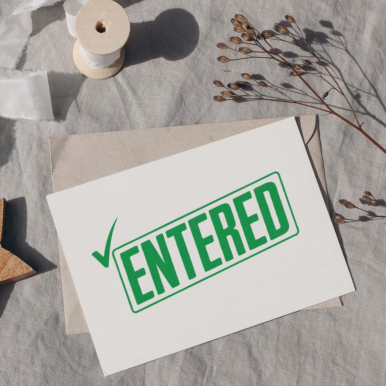 Green ENTERED rubber stamp on envelope and card for office document processing, approval, and filing.