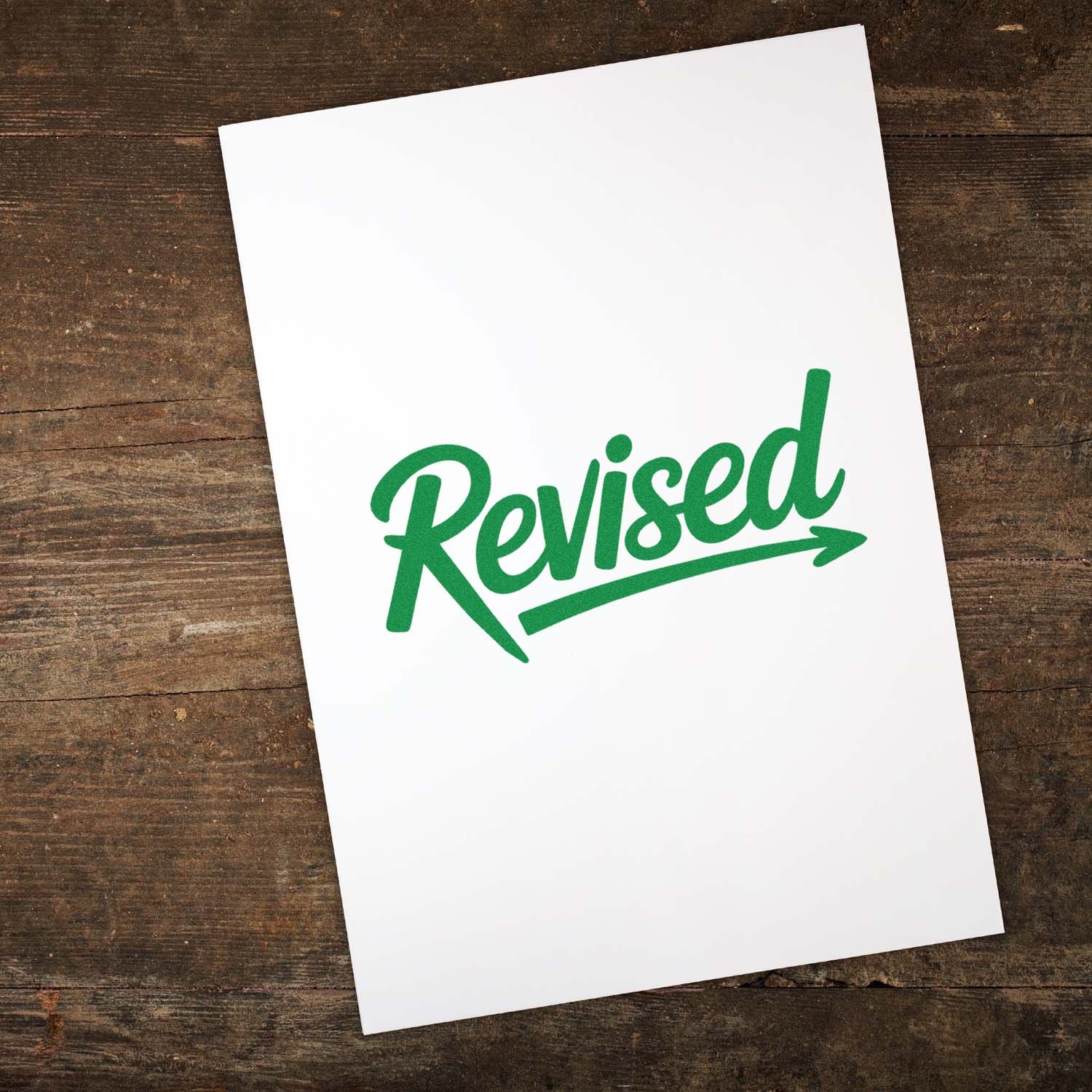 Green Revised rubber stamp impression on white paper for document review, approval, and office workflow.