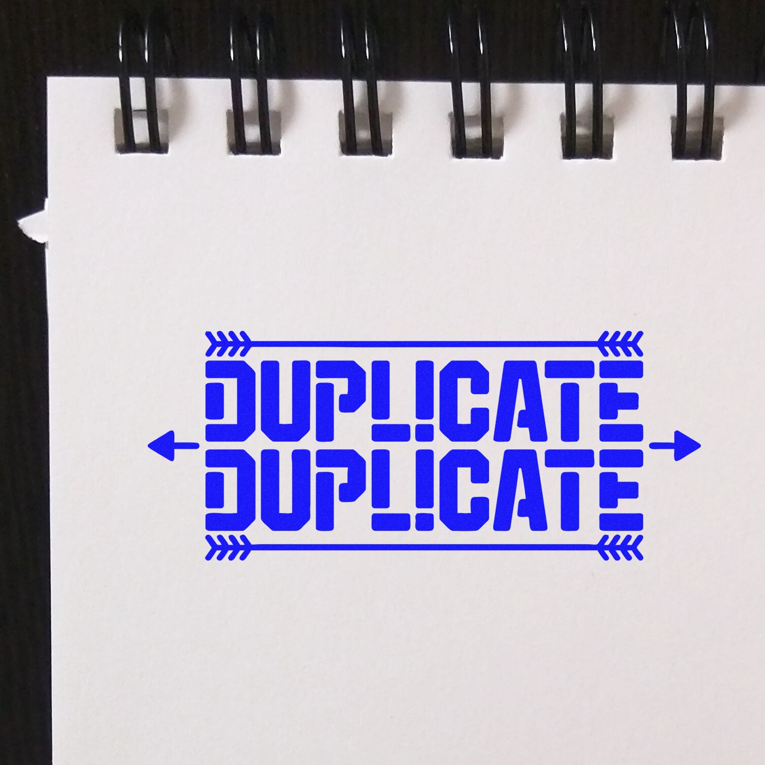 Blue DUPLICATE rubber stamp impression on notebook paper, ideal for office document labeling.
