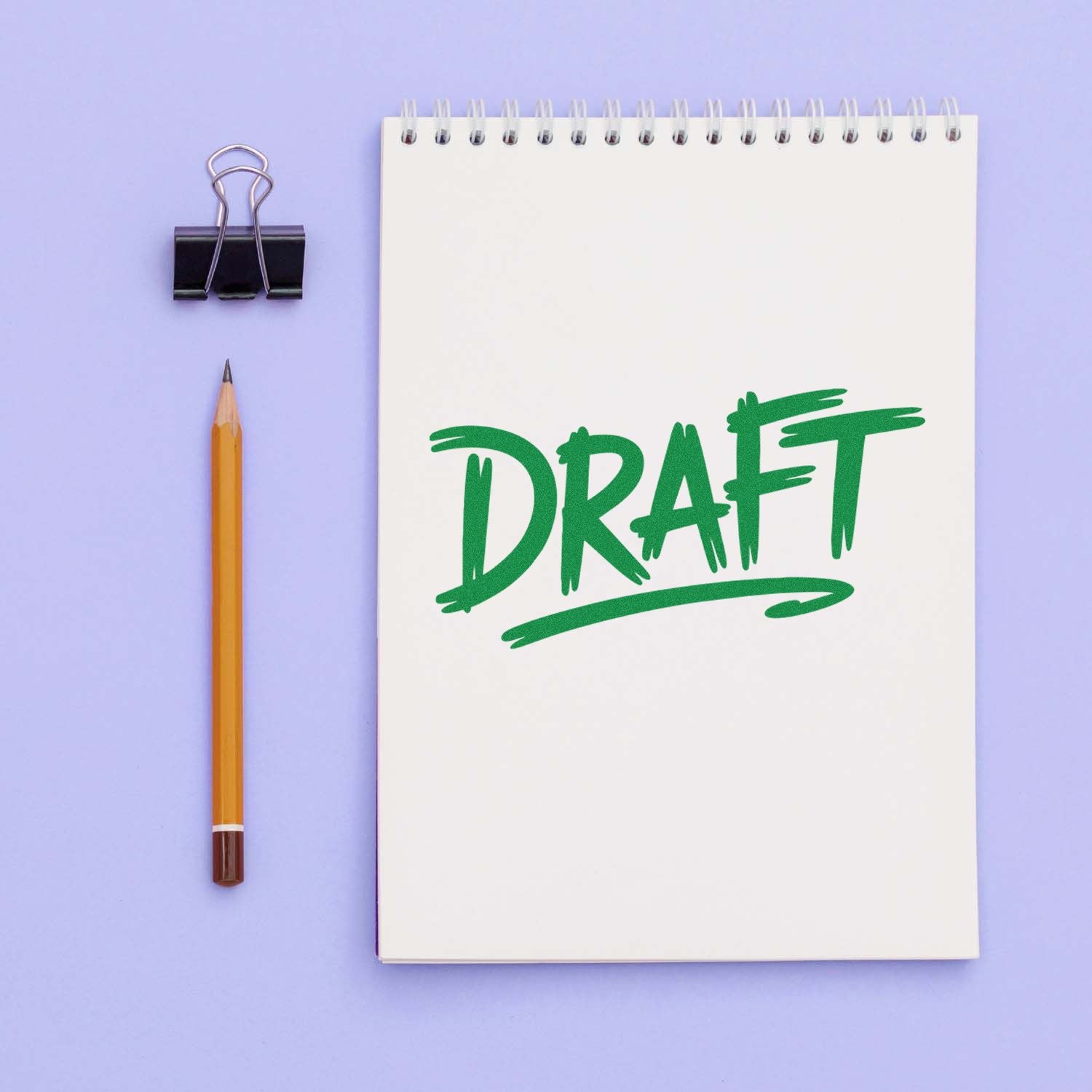 Green DRAFT rubber stamp on a spiral notebook page, ideal for marking documents, proofs, and revision status.