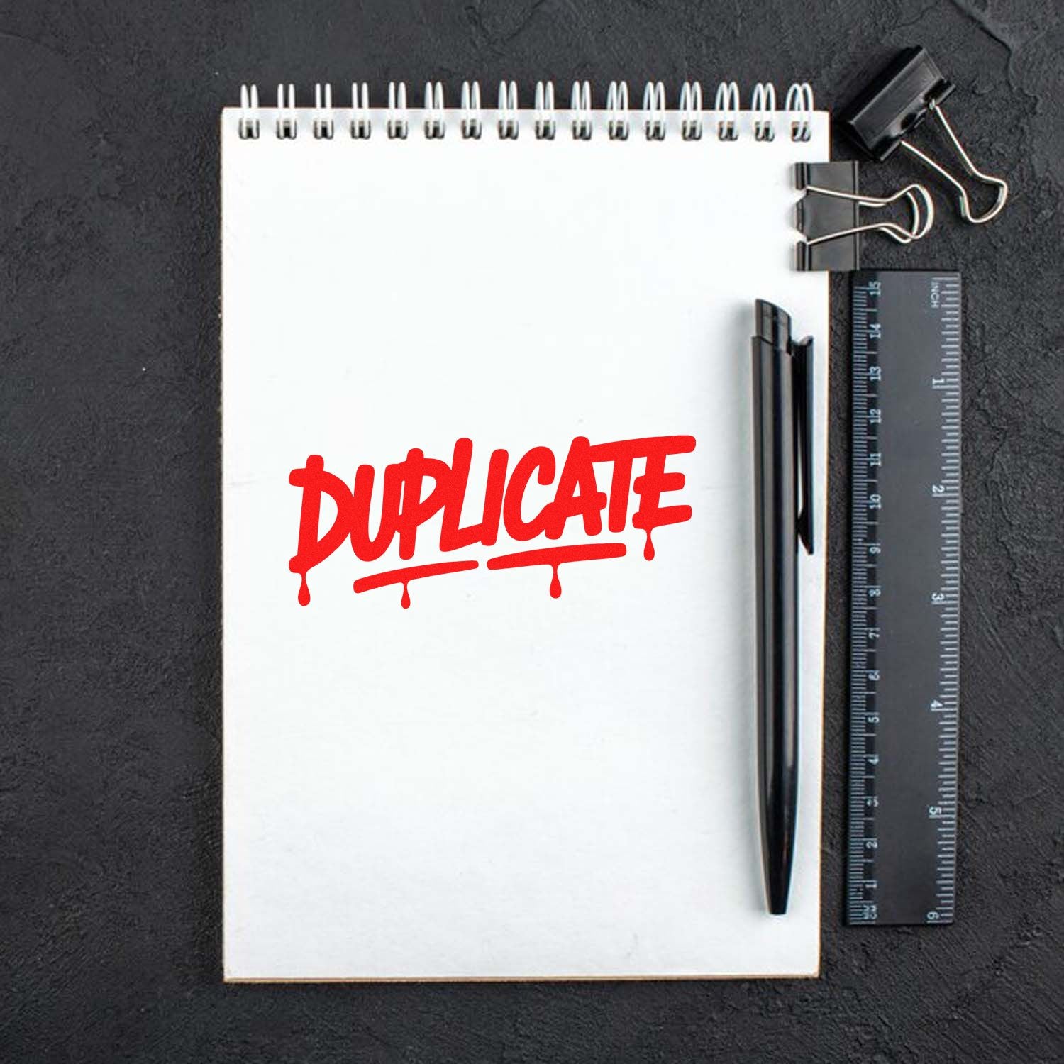 Red DUPLICATE rubber stamp impression on notepad, ideal for office document control and filing.