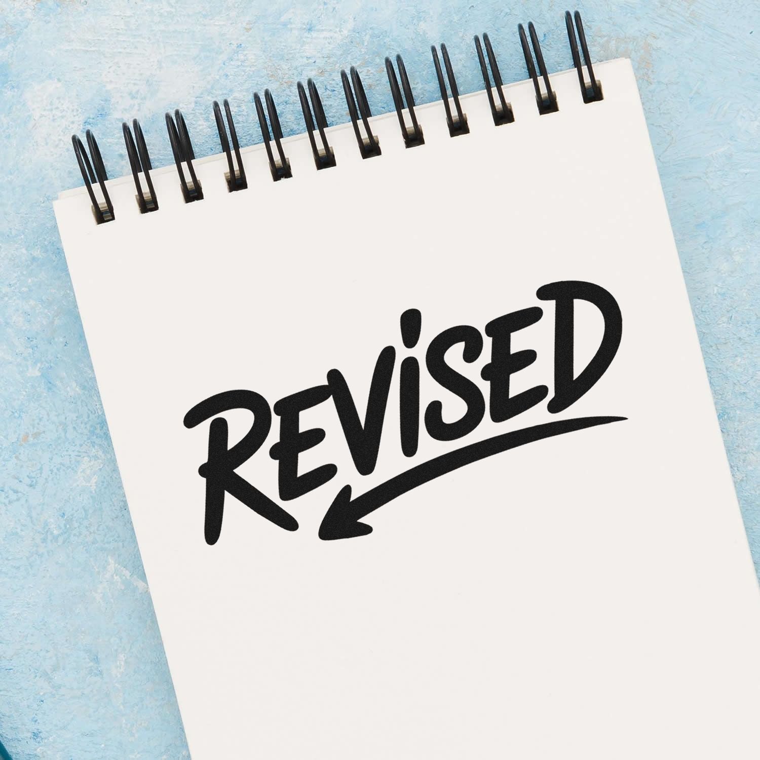 Revised rubber stamp on spiral notebook for document review and updates.