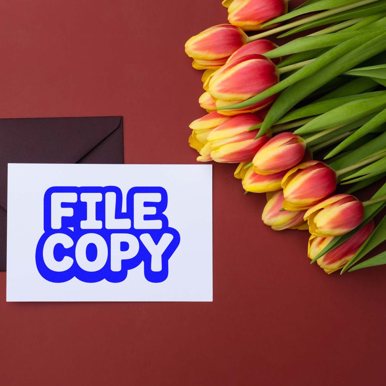 File copy rubber stamp on a card beside tulips and an envelope, for office document marking.