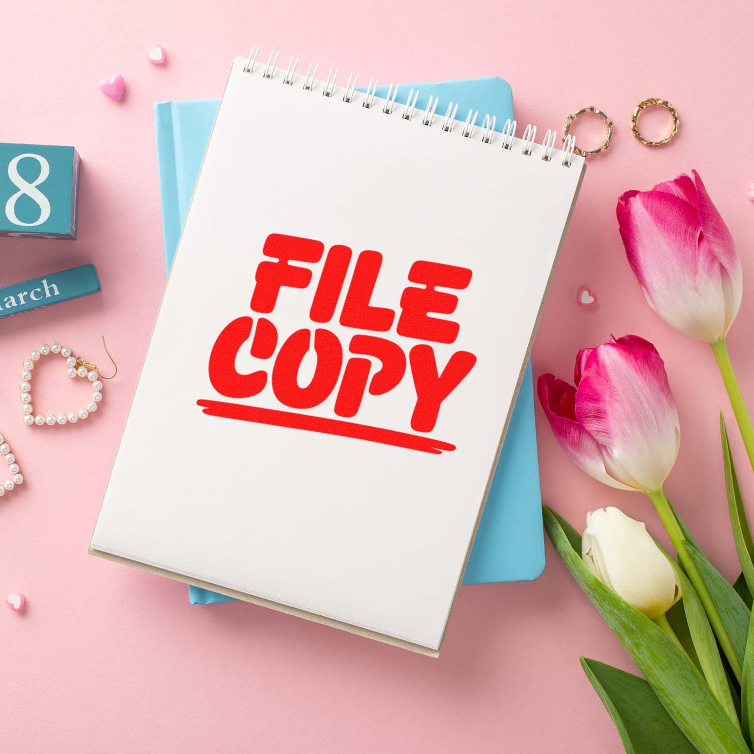 Red FILE COPY rubber stamp on notebook page with pink tulips and stationery, for office document labeling.