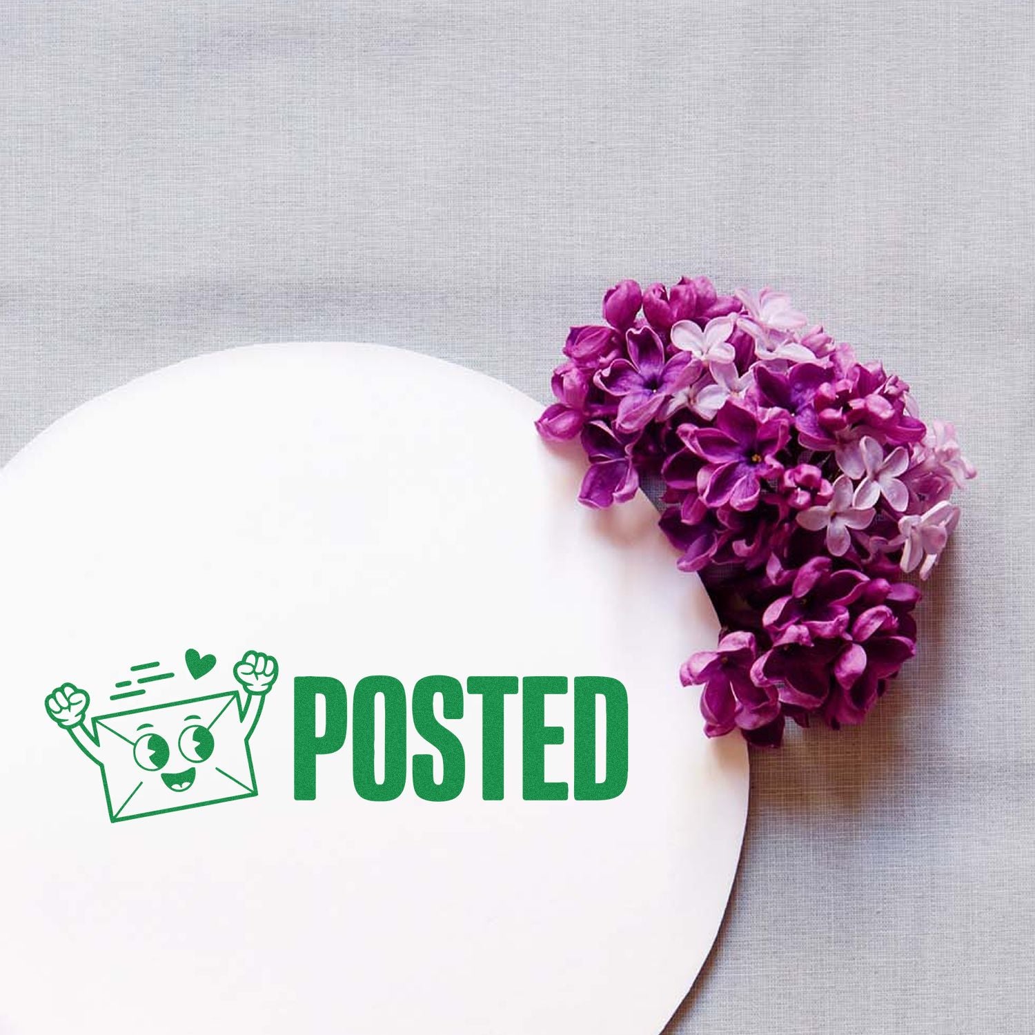 Posted rubber stamp with playful envelope icon, shown on a white card beside purple flowers.
