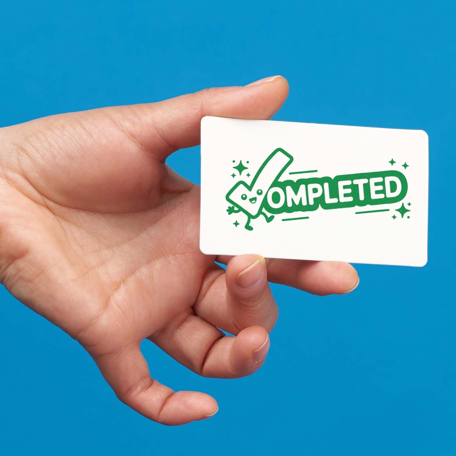 Hand holding a Completed rubber stamp design card with playful green checkmark and stars