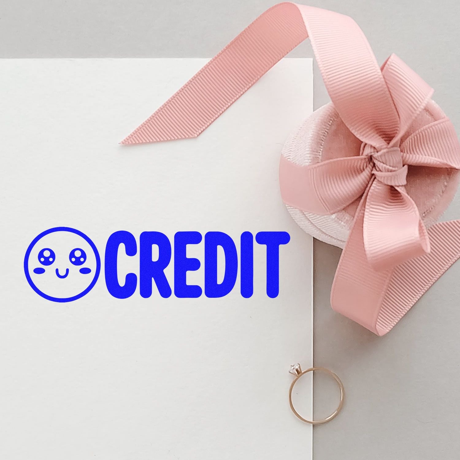 Custom rubber stamp design with credit logo on white gift card mockup and pink ribbon bow for branding and packaging.