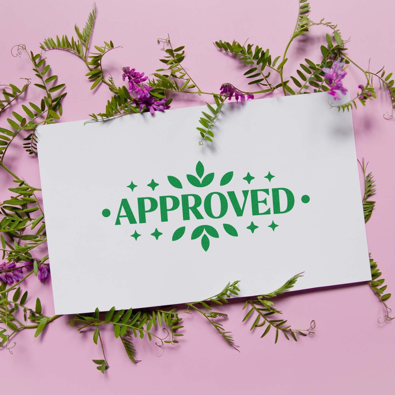 Green approved rubber stamp design on white card with floral greenery on a pink background.