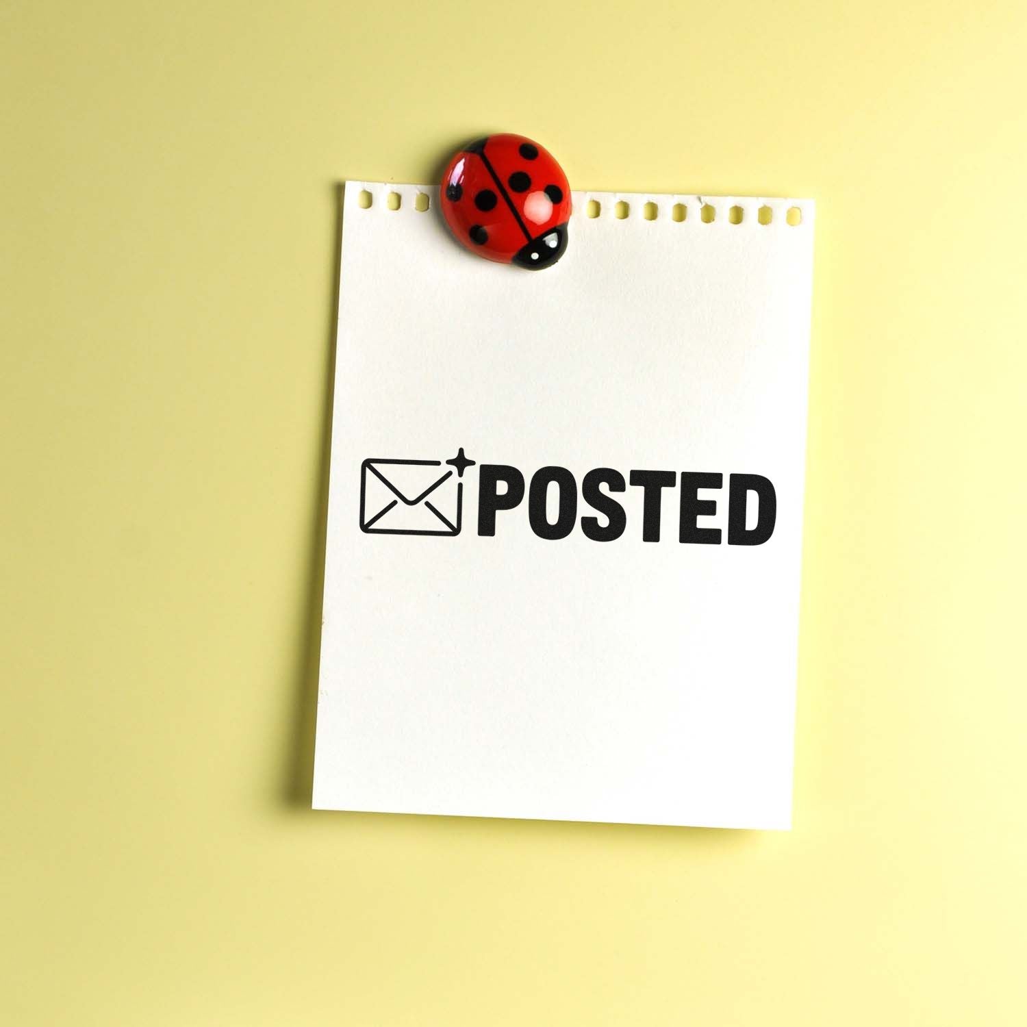Posted rubber stamp on note paper with ladybug clip, ideal for mail and office status marking.