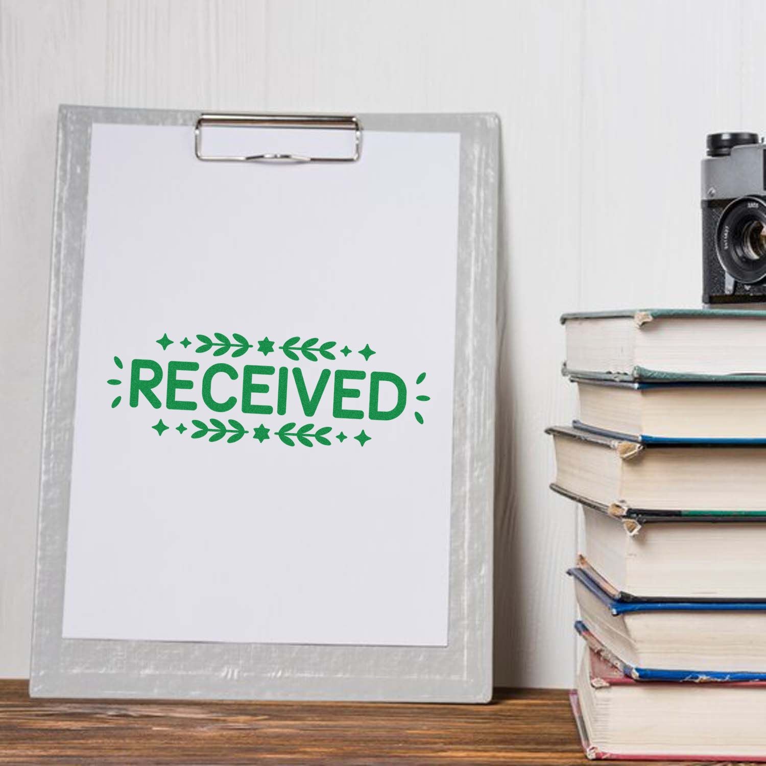 Green RECEIVED rubber stamp imprint on clipboard paper, ideal for office mail, inventory, and document processing.