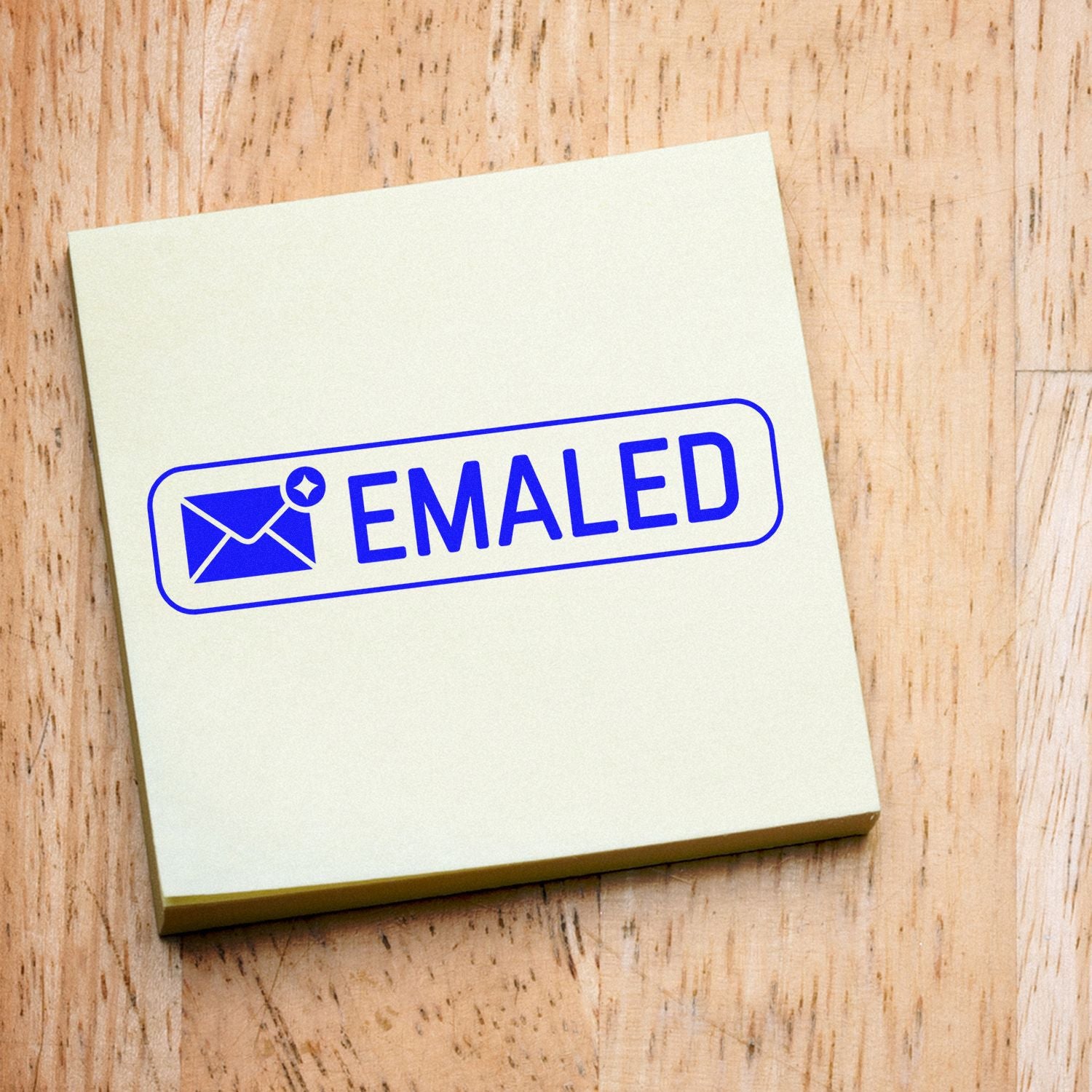 Blue EMAILED rubber stamp on notepad for office mail tracking, business communication, and workflow organization.