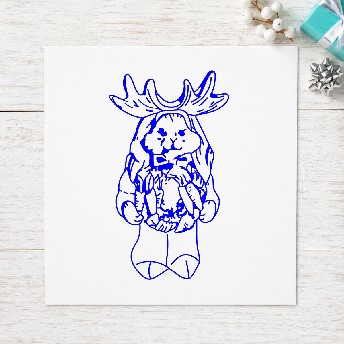 Bunny in Reindeer Costume Rubber Stamp impression in blue ink on white paper in a styled craft setting.