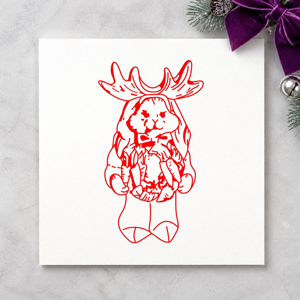 Bunny in Reindeer Costume Rubber Stamp impression in red ink on white paper in a styled craft setting.