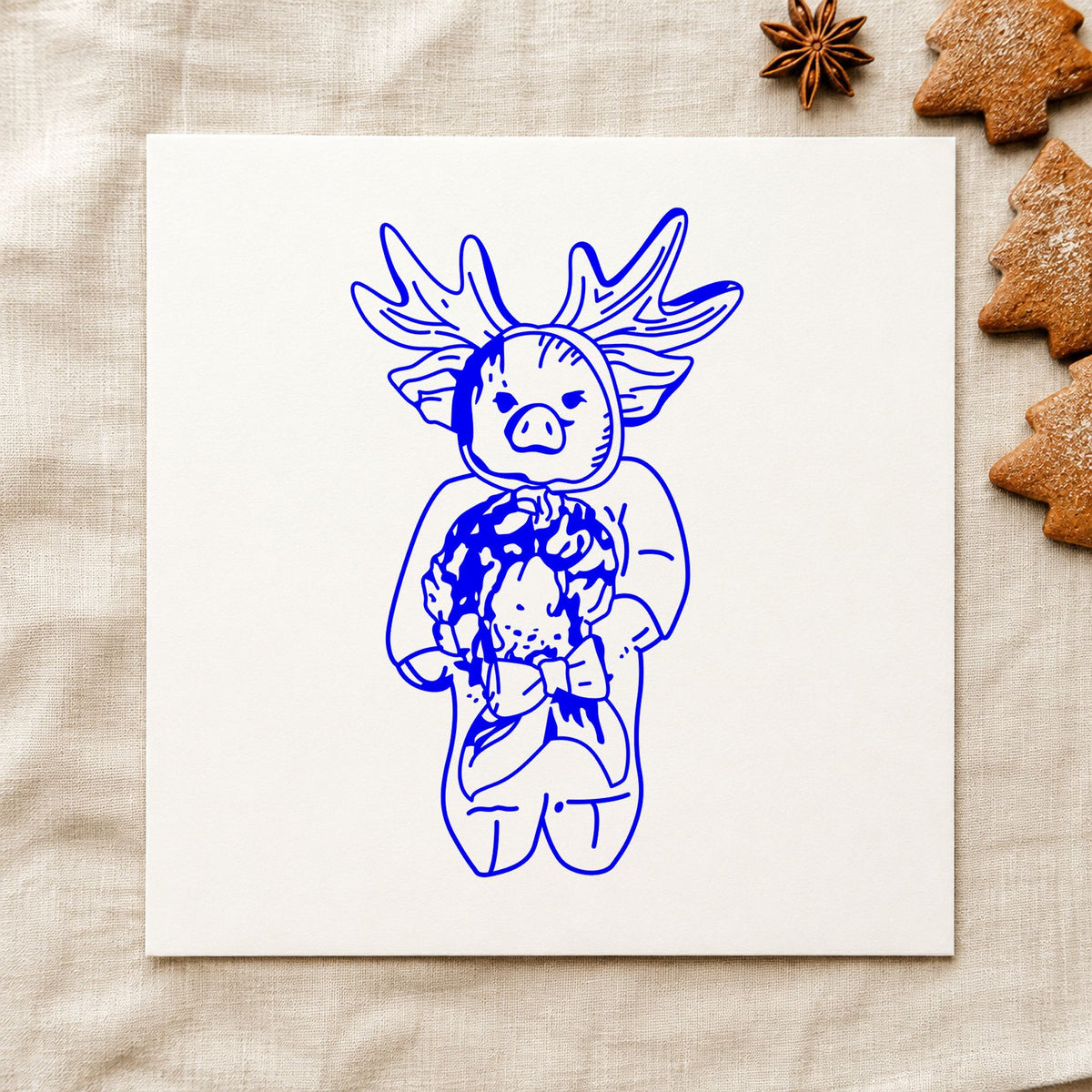 Pig in Reindeer Costume Rubber Stamp impression in blue ink on white paper in a styled craft setting.