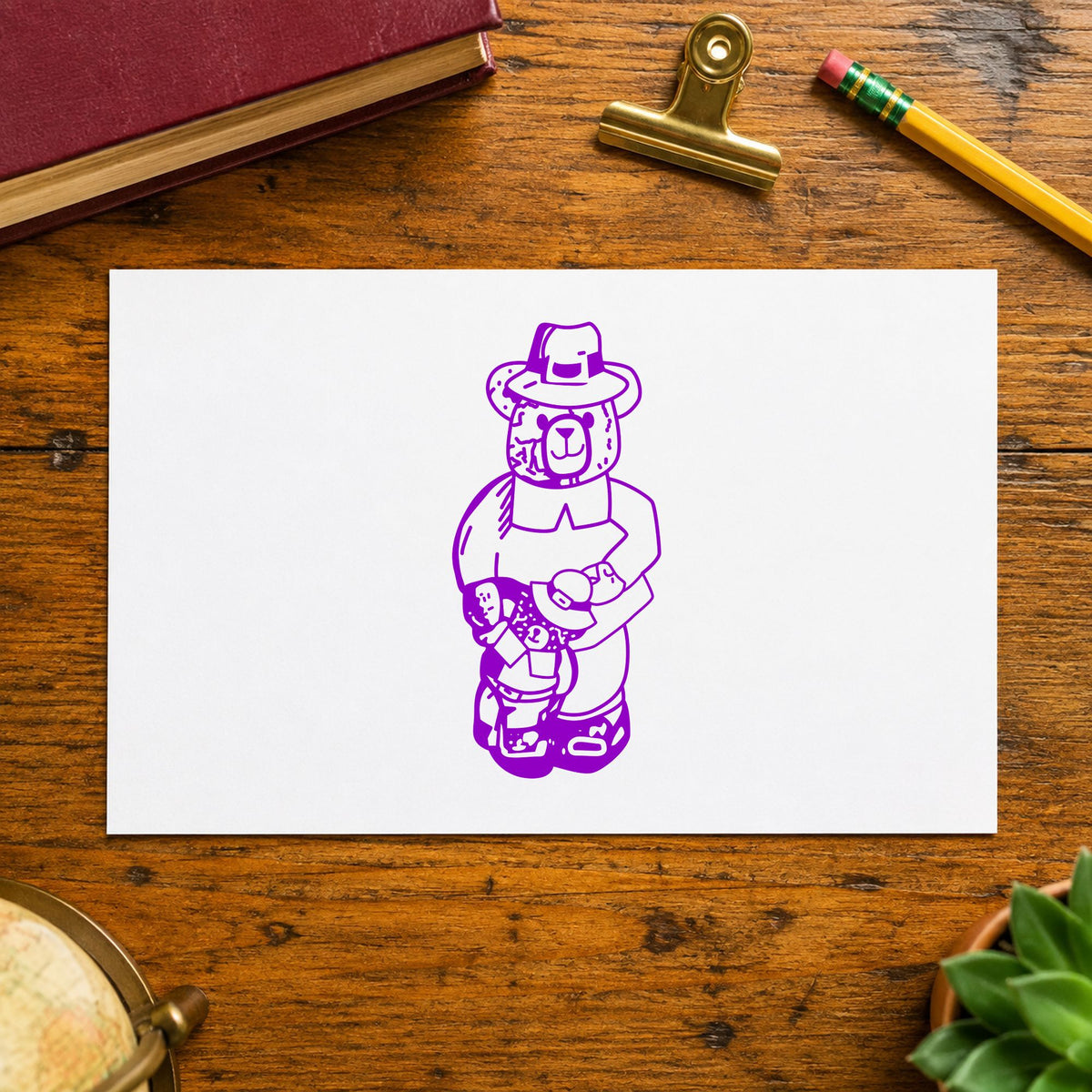Boy Pilgrim Bear with Teddy Rubber Stamp impression in purple ink on white paper in a styled craft setting.