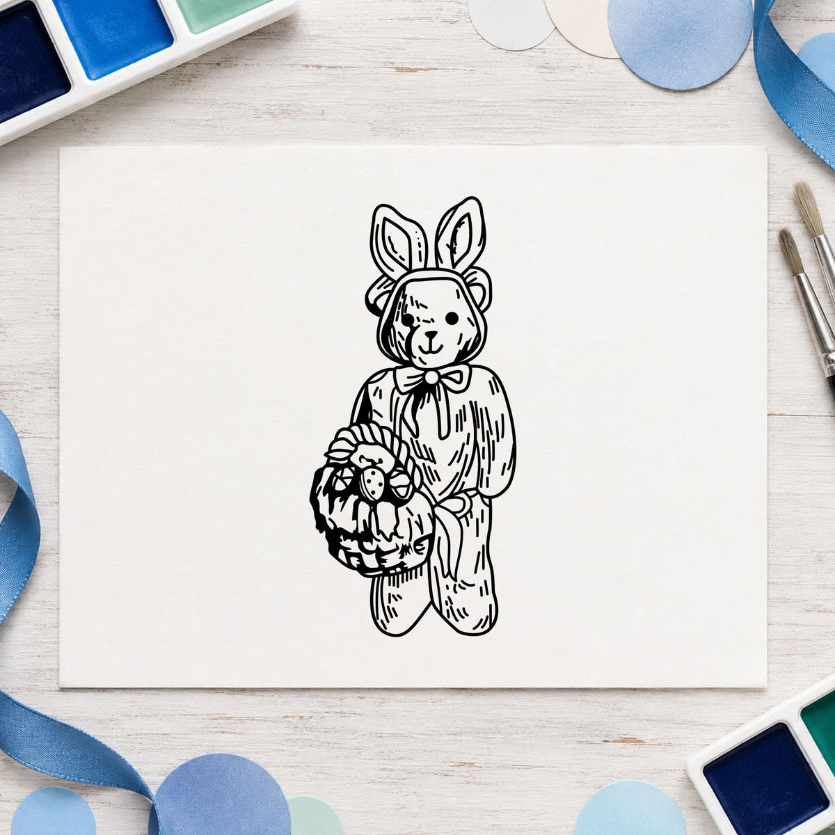 Bear in Bunny Costume with Basket Rubber Stamp impression in black ink on white paper in a styled craft setting.