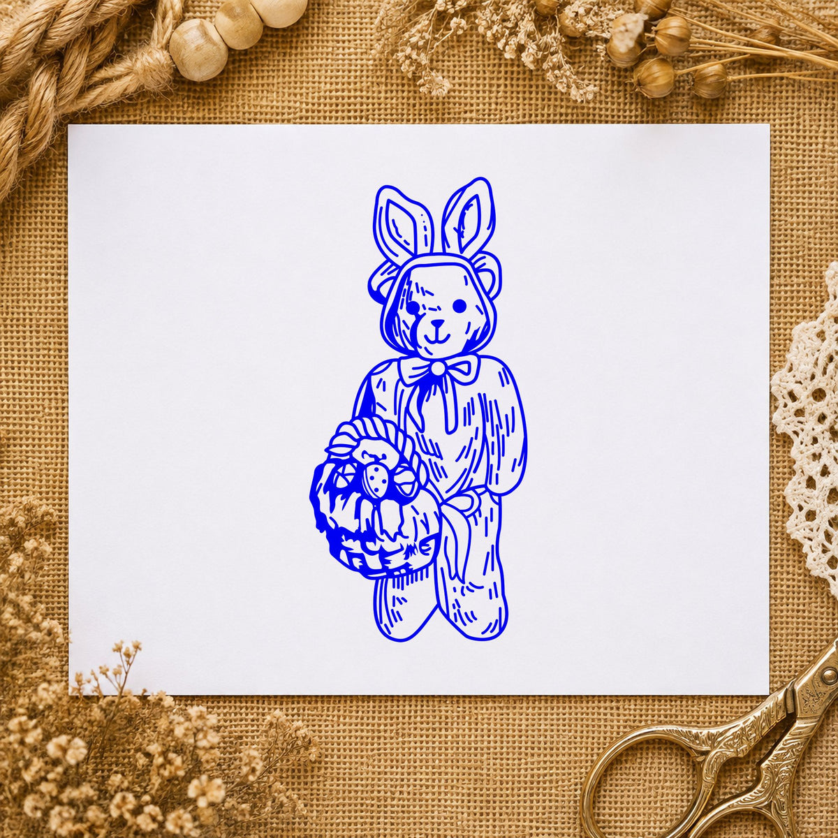 Blue bunny costume stamp impression featuring the bear in bunny costume with basket design on white paper.