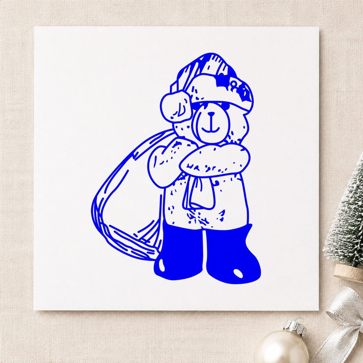 Santa Bear with Gift Bag Rubber Stamp impression in blue ink on white paper in a styled craft setting.