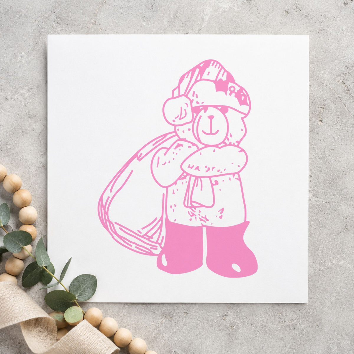 Santa Bear with Gift Bag Rubber Stamp impression in pink ink on white paper in a styled craft setting.