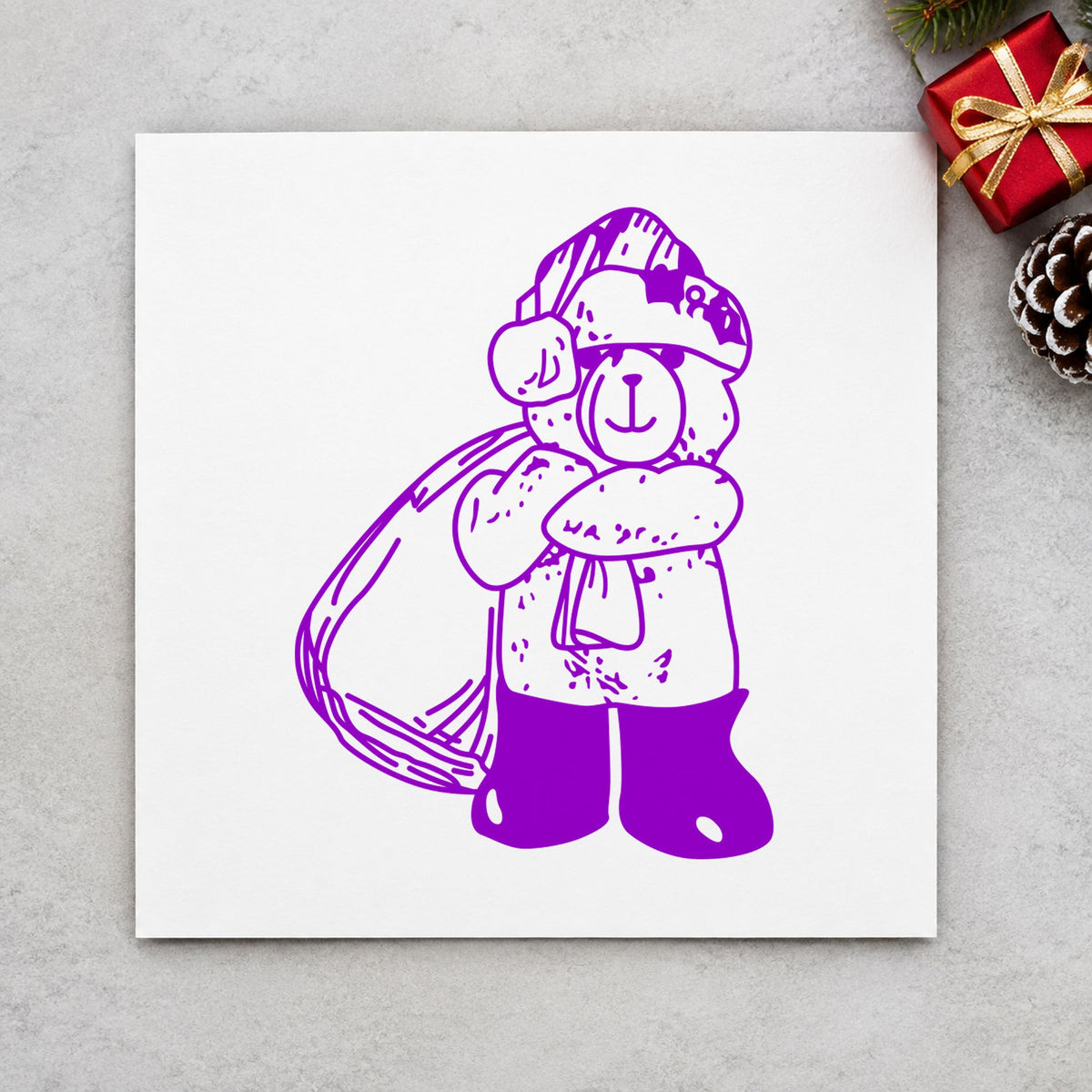 Santa Bear with Gift Bag Rubber Stamp impression in purple ink on white paper in a styled craft setting.