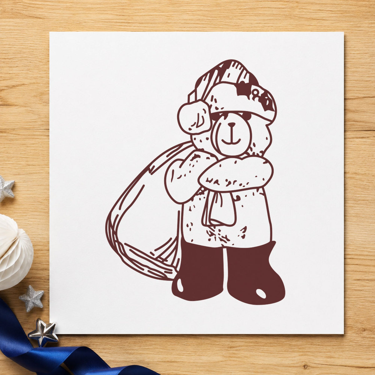 Santa Bear with Gift Bag Rubber Stamp impression in brown ink on white paper in a styled craft setting.