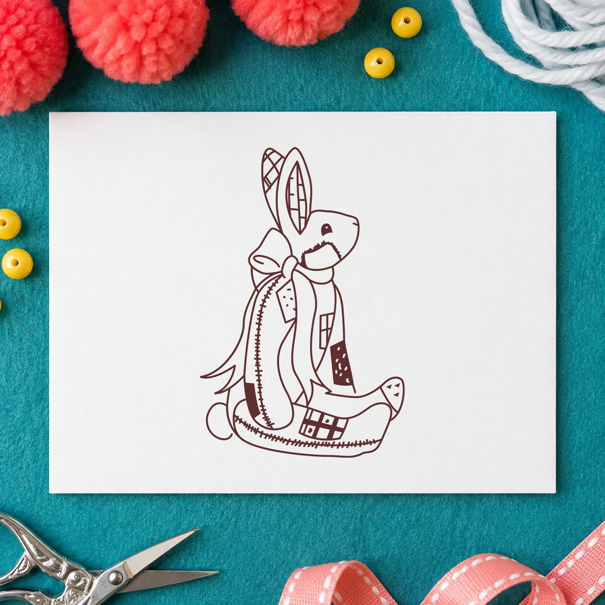 Patchwork Bunny with Bow Rubber Stamp impression in brown ink on white paper in a styled craft setting.