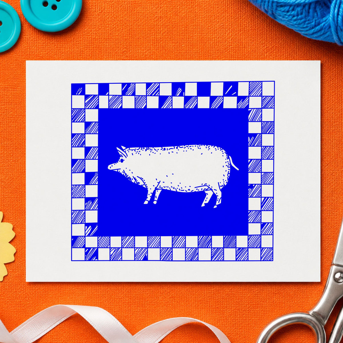 Pig with Checkered Border Rubber Stamp impression in blue ink on white paper in a styled craft setting.