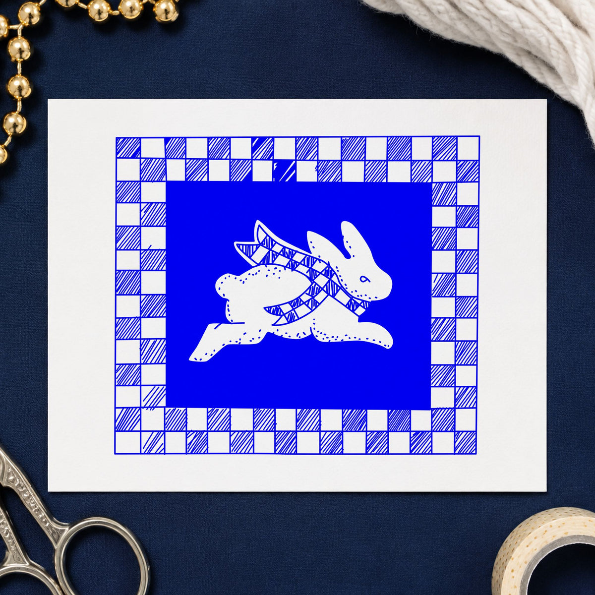 Blue country craft stamp impression featuring the rabbit with checkered border design on white paper.