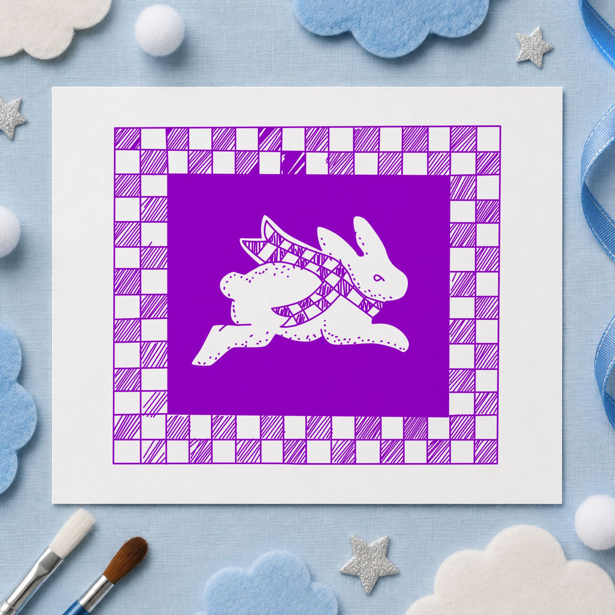 Rabbit with Checkered Border Rubber Stamp impression in purple ink on white paper in a styled craft setting.