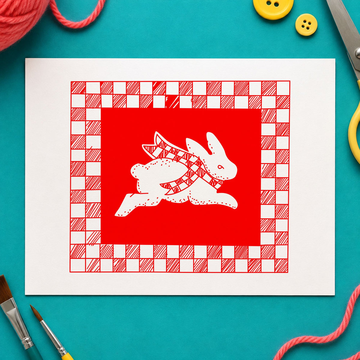 Rabbit with Checkered Border Rubber Stamp impression in red ink on white paper in a styled craft setting.