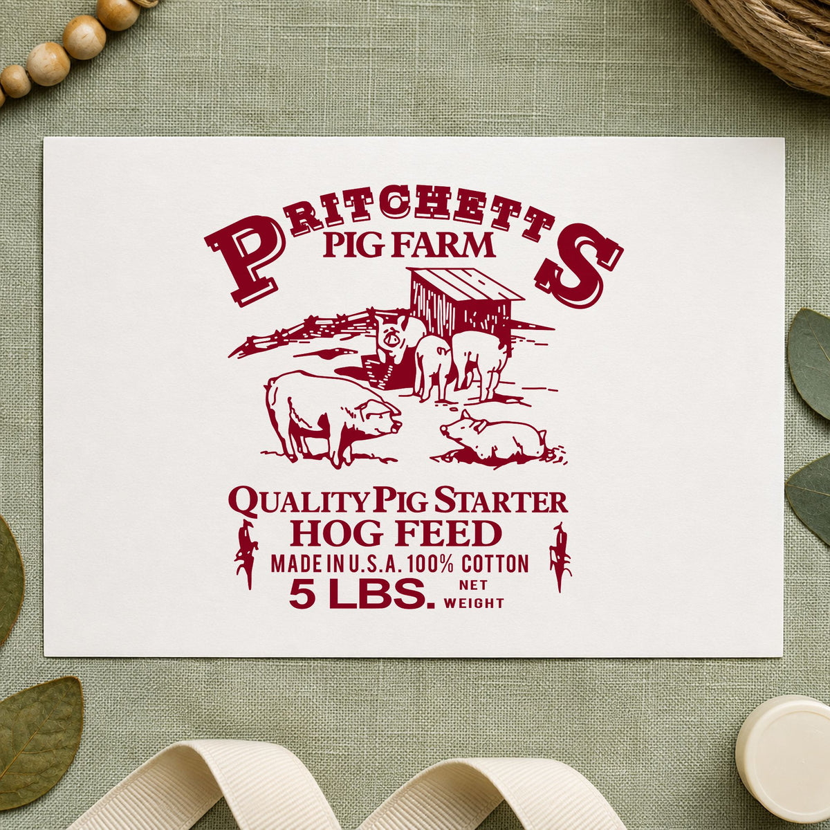 Hog Feed Label Rubber Stamp impression in burgundy ink on white paper in a styled craft setting.