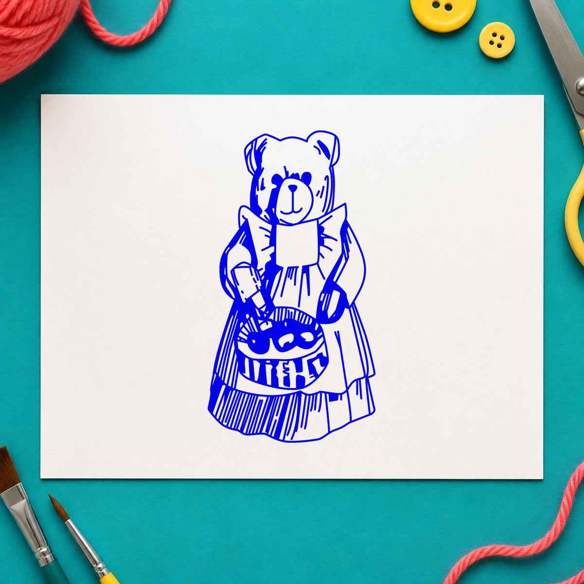 Blue harvest craft stamp impression featuring the country bear with produce basket design on white paper.