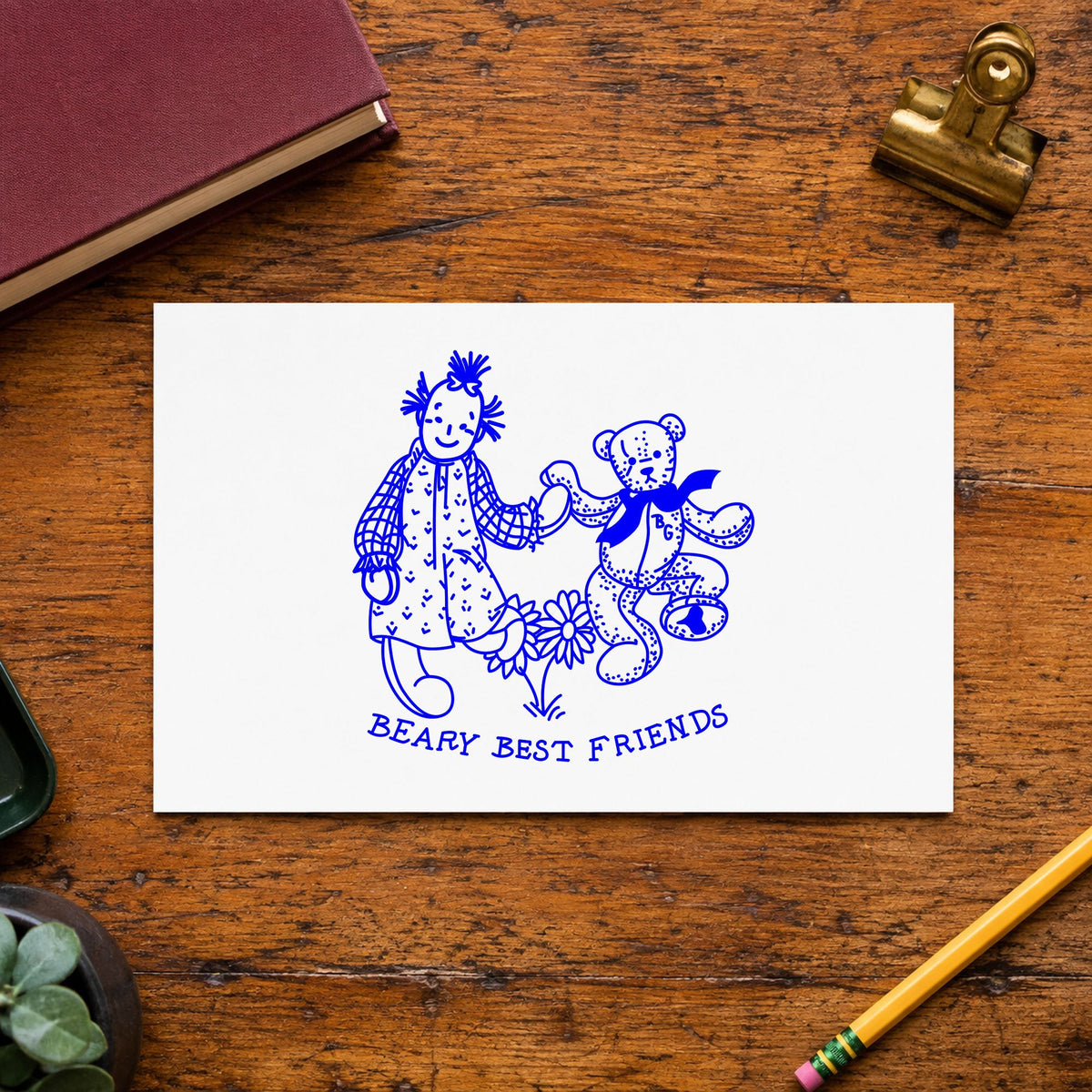 Beary Best Friends Bear and Doll Rubber Stamp impression in blue ink on white paper in a styled craft setting.