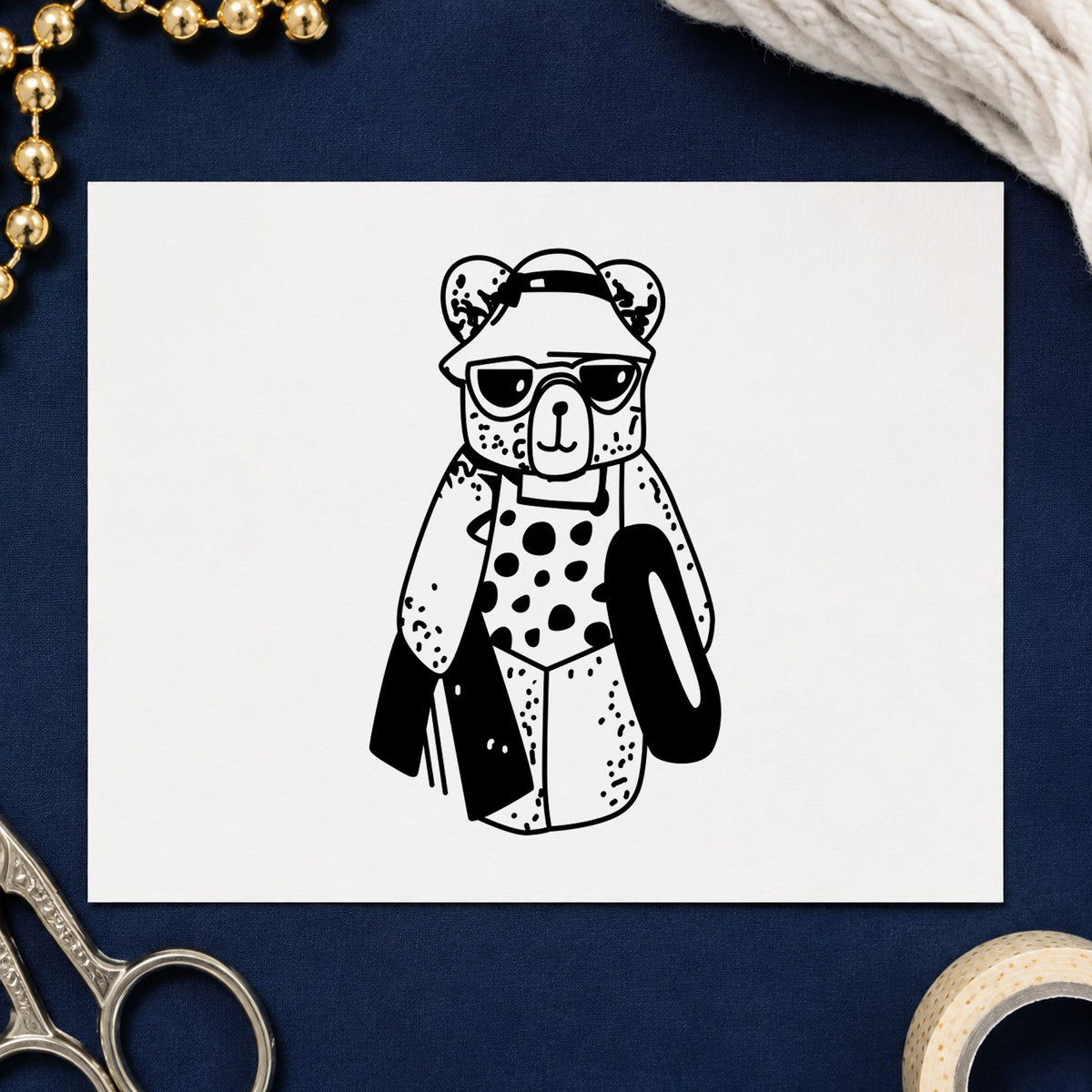 Black impression from a swimming bear stamp, featuring the bear with inner tube design on white paper.