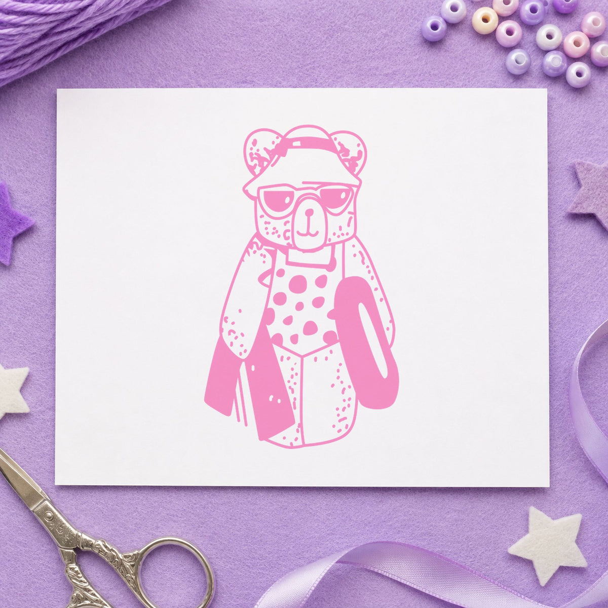 Bear with Inner Tube Rubber Stamp impression in pink ink on white paper in a styled craft setting.