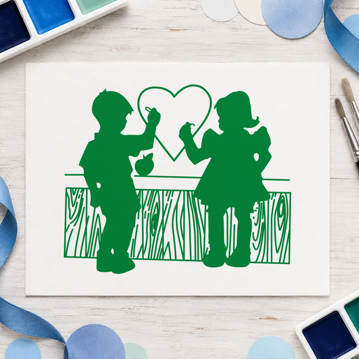 Boy and Girl Drawing a Heart Rubber Stamp impression in green ink on white paper in a styled craft setting.