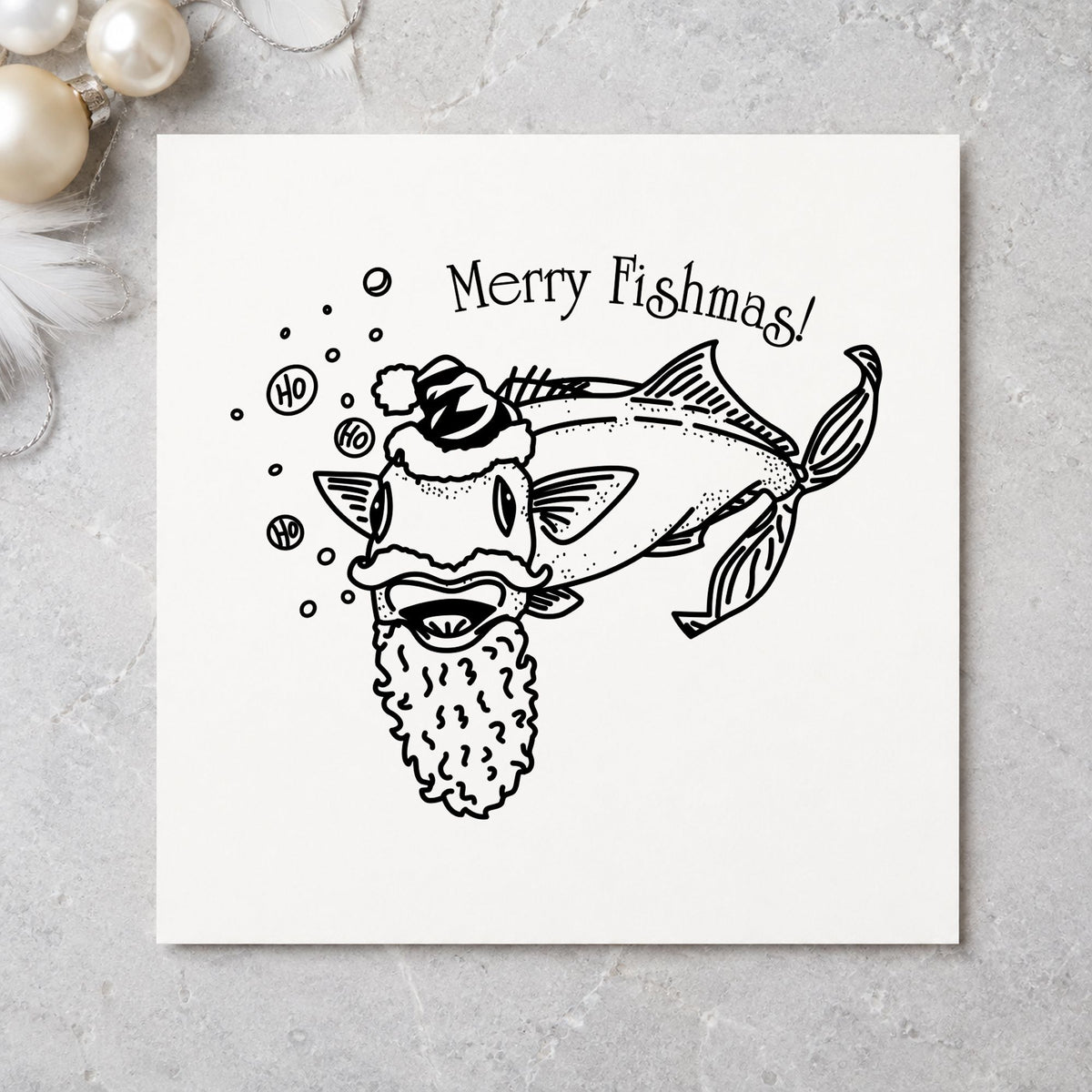 Merry Fishmas Catfish Rubber Stamp impression in black ink on white paper in a styled craft setting.