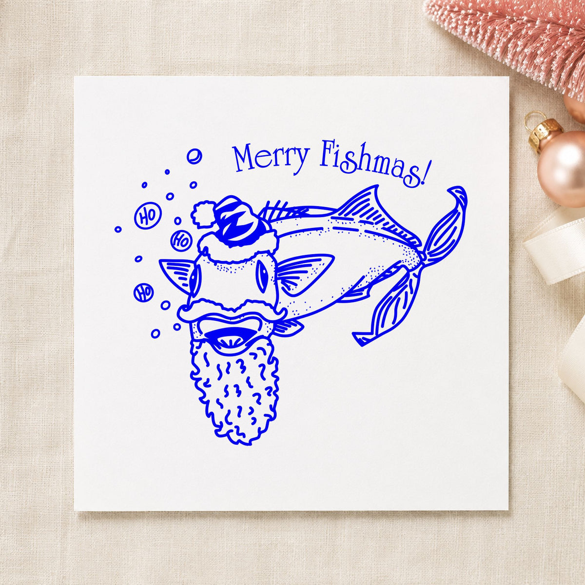 Merry Fishmas Catfish Rubber Stamp impression in blue ink on white paper in a styled craft setting.