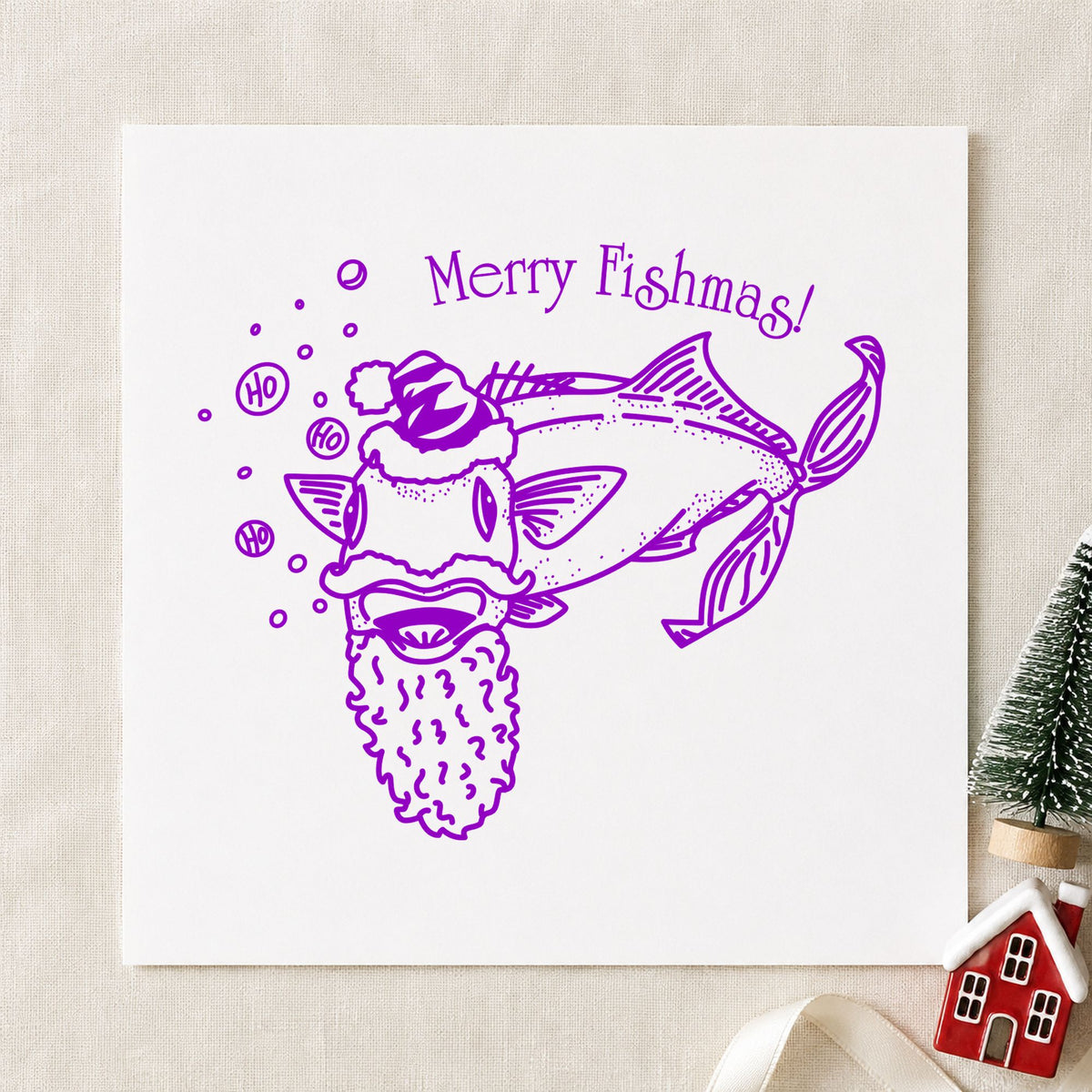 Merry Fishmas Catfish Rubber Stamp impression in purple ink on white paper in a styled craft setting.