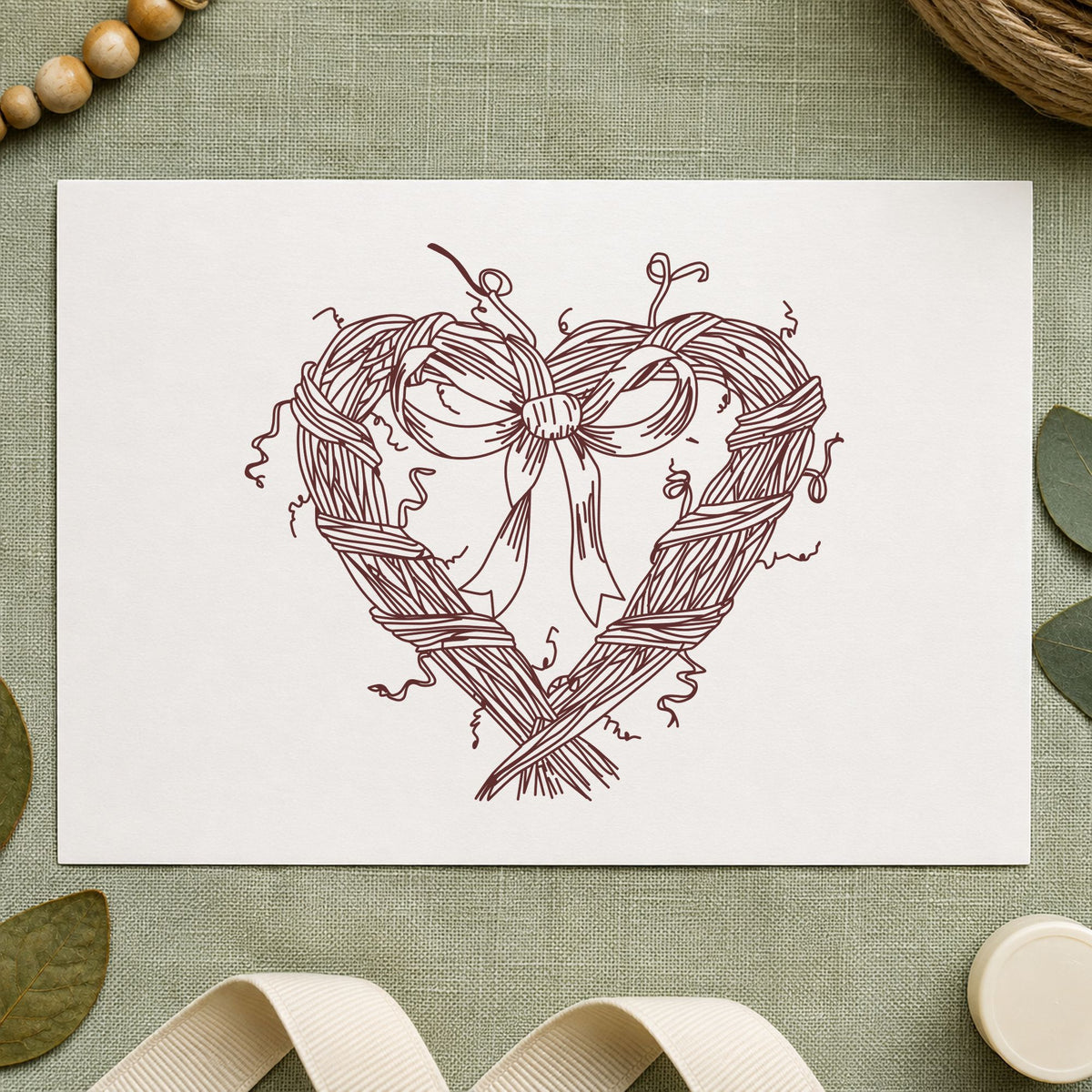 Heart Wreath with Bow Rubber Stamp impression in brown ink on white paper in a styled craft setting.