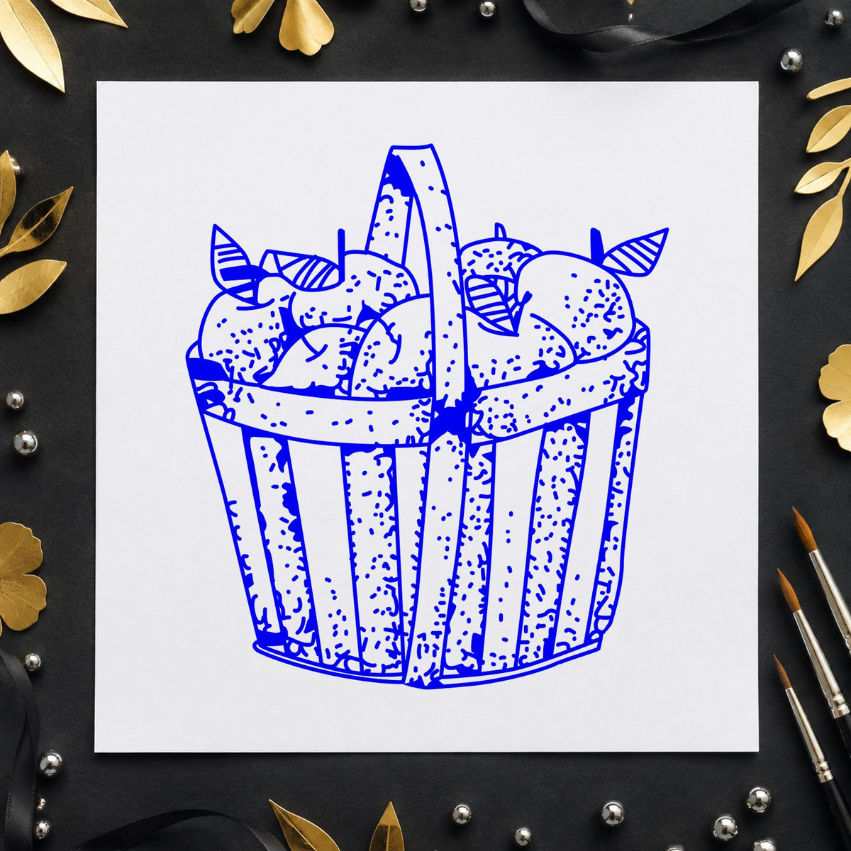 Slatted Apple Basket Rubber Stamp impression in blue ink on white paper in a styled craft setting.