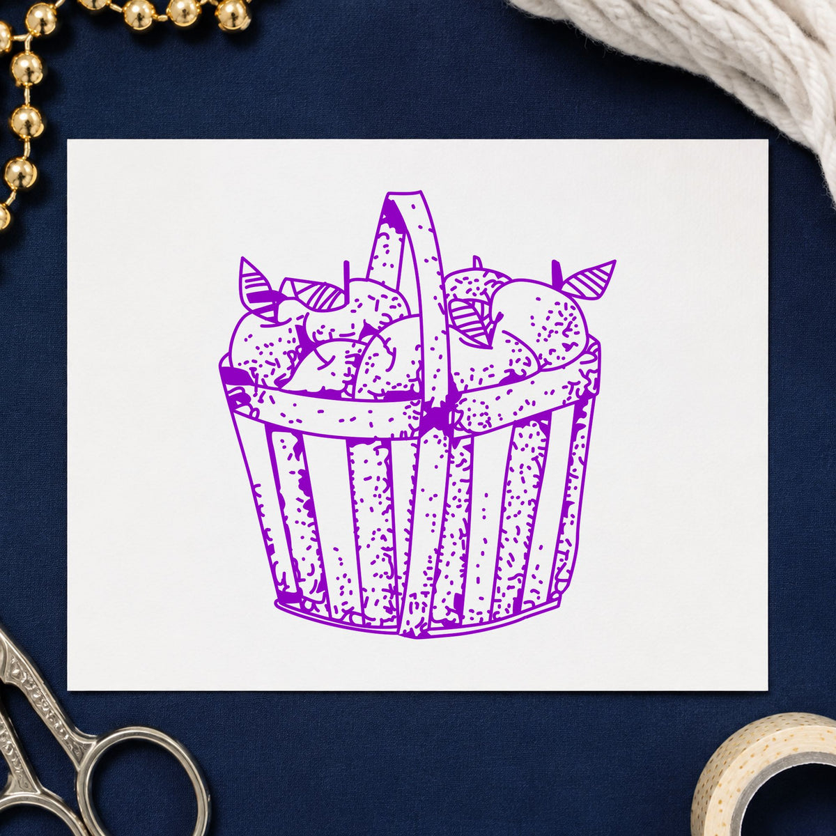 Slatted Apple Basket Rubber Stamp impression in purple ink on white paper in a styled craft setting.